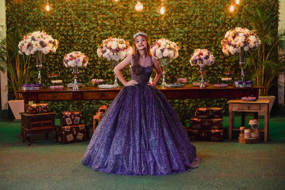 Debutante de vestido lilás em frente à mesa de doces