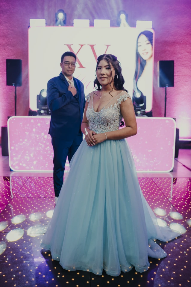 Debutante ao lado de um convidado em frente ao painel de 15 anos
