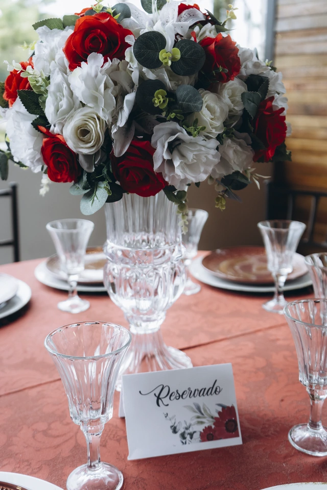 Arranjo de rosas vermelhas e brancas sobre a mesa posta
