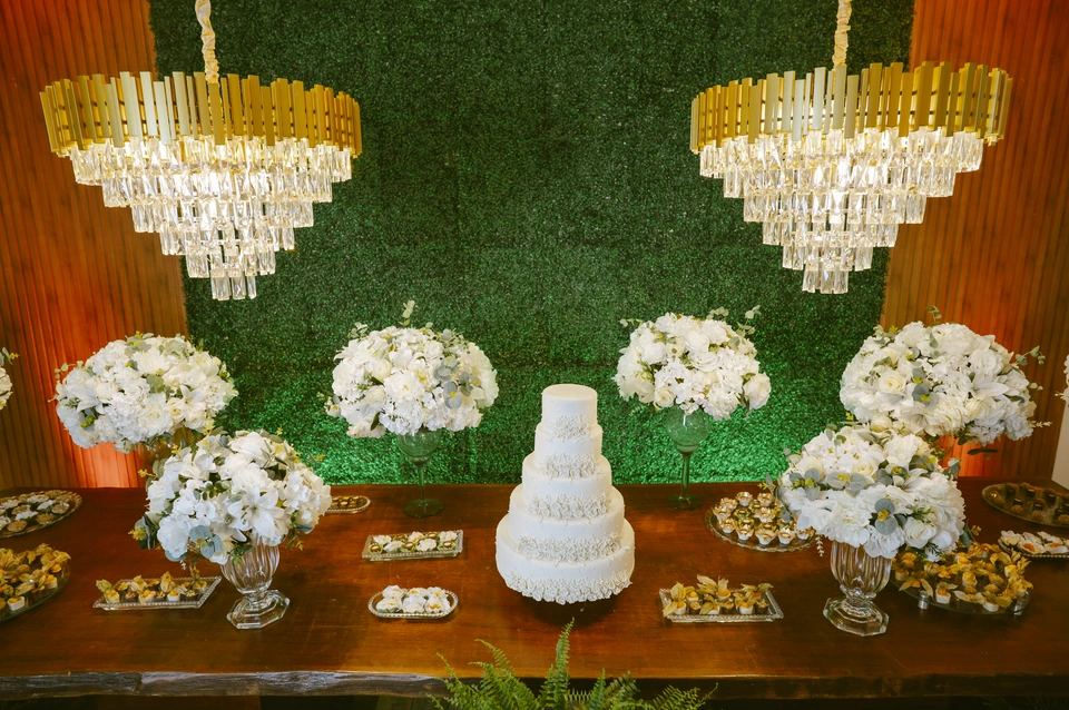 Mesa do bolo de casamento com flores brancas e lustres de cristal