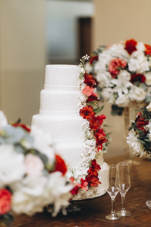 Bolo de casamento branco decorado com flores vermelhas