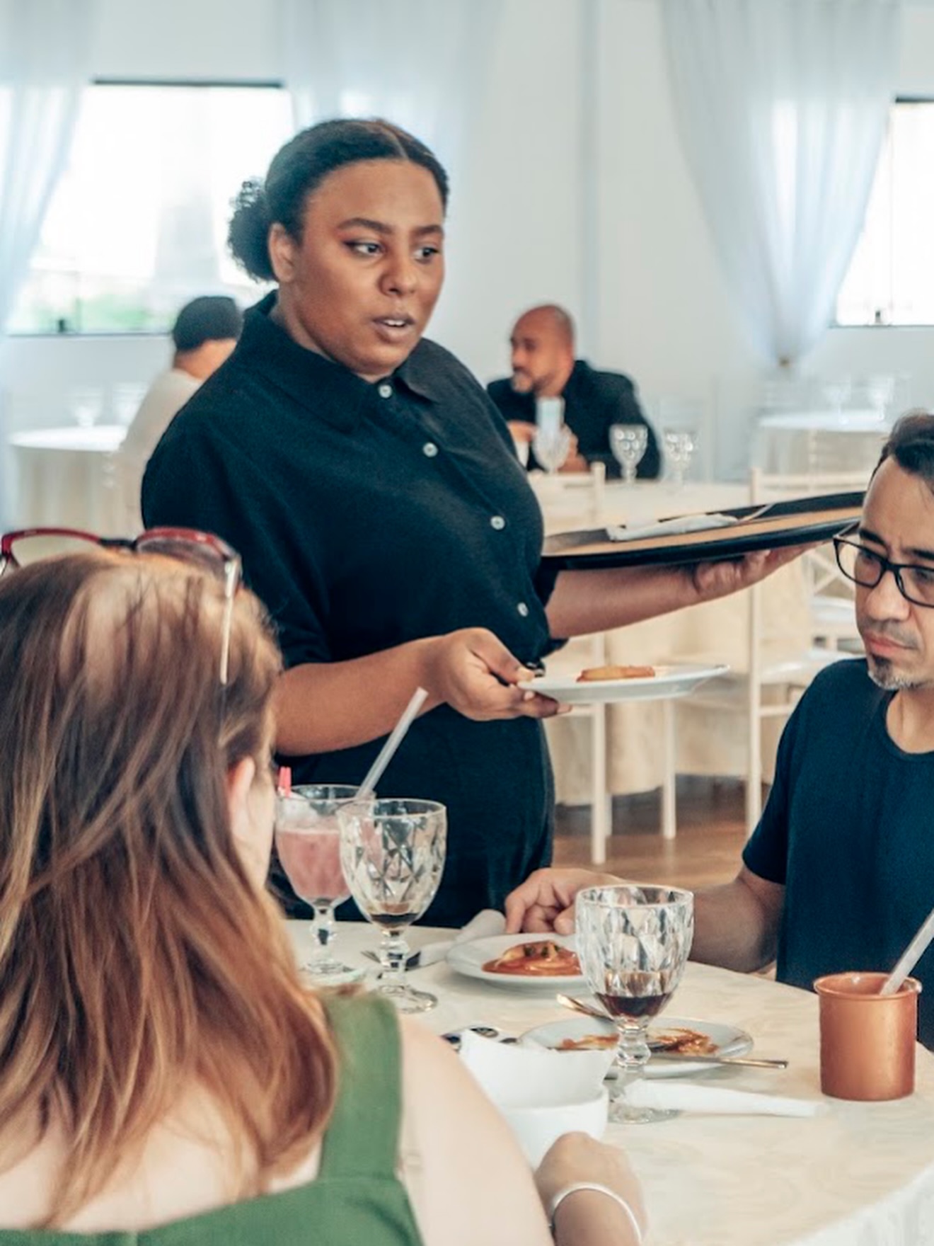 Garçonete atendendo convidados à mesa